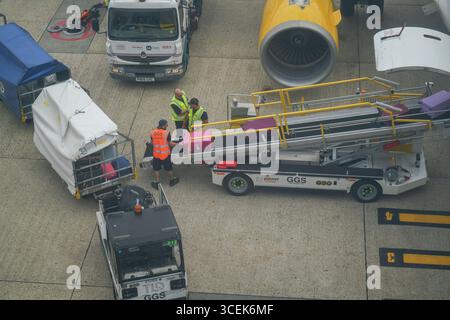 Gatwick, Regno Unito 18 agosto 2025. Portabagagli che scaricano i bagagli dei passeggeri da un aereo all'aeroporto di Gatwick. I gestori dei bagagli rappresentati dall' Unione delle TIC hanno sospeso lo sciopero che avrebbe avuto luogo dal 22 -26 agosto dopo che è stata presentata una nuova offerta di pagamento . Amer Ghazzal/Alamy Live News Foto Stock