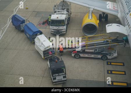 Gatwick, Regno Unito 18 agosto 2025. Portabagagli che scaricano i bagagli dei passeggeri da un aereo all'aeroporto di Gatwick. I gestori dei bagagli rappresentati dall' Unione delle TIC hanno sospeso lo sciopero che avrebbe avuto luogo dal 22 -26 agosto dopo che è stata presentata una nuova offerta di pagamento . Amer Ghazzal/Alamy Live News Foto Stock