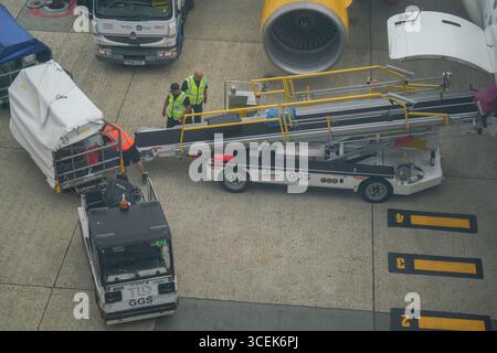 Gatwick, Regno Unito 18 agosto 2025. Portabagagli che scaricano i bagagli dei passeggeri da un aereo all'aeroporto di Gatwick. I gestori dei bagagli rappresentati dall' Unione delle TIC hanno sospeso lo sciopero che avrebbe avuto luogo dal 22 -26 agosto dopo che è stata presentata una nuova offerta di pagamento . Amer Ghazzal/Alamy Live News Foto Stock