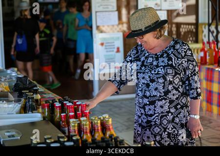 Marigo Bay, Saint Lucia - 27 dicembre 2015: Un turista sfoglia una variopinta selezione di salse e condimenti locali in un vivace mercato nella Baia di Marigot, Foto Stock