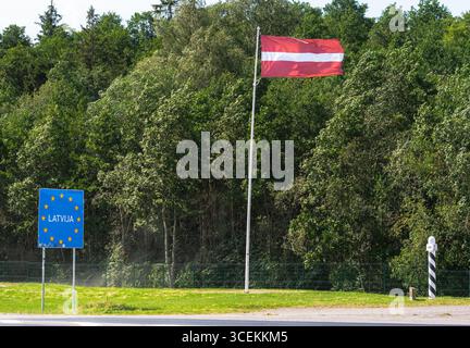 Valico di frontiera lettone contrassegnato da un cartello dell'Unione europea con la Latvija e la bandiera nazionale lettone che la accompagna Foto Stock