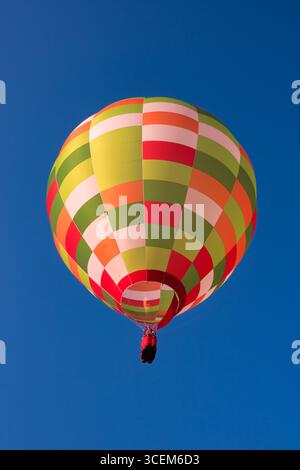Il colorato pallone aerostatico vola in aria contro il cielo blu Foto Stock