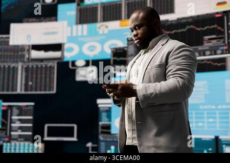 Leader aziendale maschile di colore in un ambiente digitale focalizzato su grafici, lavorando sull'analisi della pianificazione strategica per la redditività e le prestazioni. Inquietudine e previsioni fintech. Foto Stock