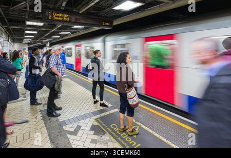 Treno che supera le persone in attesa sul binario, stazione della metropolitana Victoria, City of Westminster, Londra, Inghilterra, Regno Unito Foto Stock