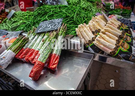 VALENCIA, SPAGNA - 15 APRILE 2025: Bancarella del mercato a Valencia, Spagna, con fasci di asparagi verdi e asparagi bianchi confezionati in vendita, vista su S. Foto Stock