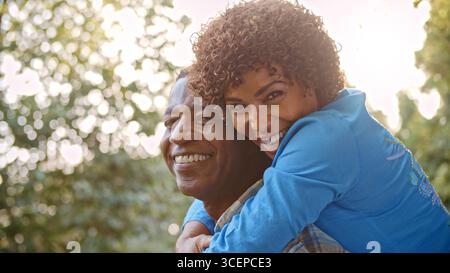 Ritratto all'aperto di coppia matura con donna che abbraccia l'uomo da dietro con Lens Flare Foto Stock
