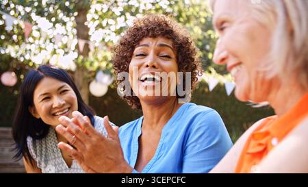 Primo piano di amiche mature e sorridenti che socializzano in Backyard Together Foto Stock
