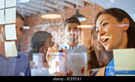 Imprenditrice idee di scrittura su schermo di vetro durante la riunione Foto Stock