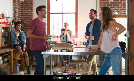 Gruppo di giovani amici per un caffè nell'appartamento Loft Foto Stock