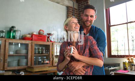 Coppia giovane amorevole che abbraccia la cucina dell'appartamento open space Foto Stock