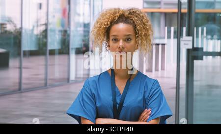 Ritratto di infermiera donna seria che indossa scrub in piedi nel moderno edificio dell'ospedale Foto Stock