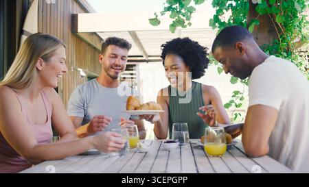 Gruppo di amici culturali sorridenti che fanno colazione all'aperto a casa Foto Stock