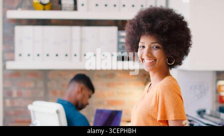 Ritratto di una giovane donna d'affari sorridente che lavora alla scrivania in ufficio Foto Stock