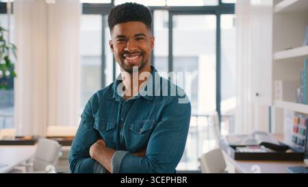 Ritratto di giovane uomo d'affari sorridente in piedi in Modern Office Foto Stock