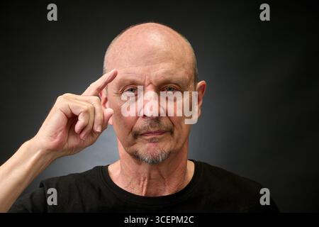 Ritratto ravvicinato di un uomo anziano in studio che fa un salut con un'illuminazione vintage in stile Harcourt Foto Stock