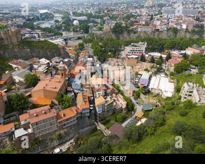 Vista panoramica su una città con fiume, tetti colorati e verdi colline, vista aerea, città vecchia, fiume Kura, Tbilisi, Tbilisi, Georgia Foto Stock