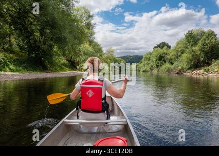 Monmouthshire, Galles, Regno Unito. Una donna che pagaia su una canoa aperta per due persone sul fiume Wye. Un passatempo ricreativo popolare nella valle di Wye Foto Stock