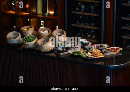 Assortimento di piatti cinesi. Spaghetti cinesi, riso fritto, gnocchi, dim sum, involtini primavera. Famosi piatti della cucina cinese su sfondo nero Foto Stock