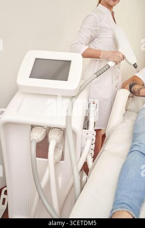 Tecnico donna che esegue la procedura di coolsculpting su pazienti adulti che utilizzano macchinari moderni in clinica. Foto Stock