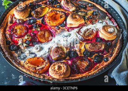 Una crostata o una torta aperta con mirtilli, fichi, prugne e albicocche in un piatto da forno su sfondo grigio. Primo piano. Foto di alta qualità Foto Stock