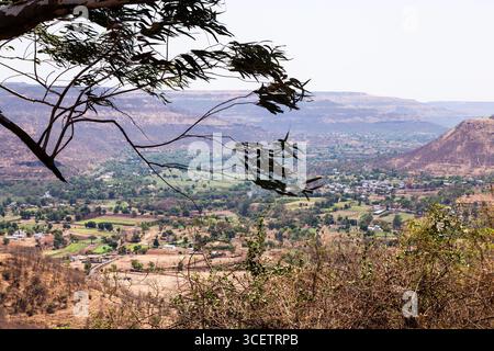 Questa immagine mostra una pittoresca valle circondata da colline, con un lussureggiante paesaggio verde e insediamenti umani sparsi Foto Stock