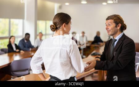 Manager bianco di mezza età che dà il benvenuto a una nuova dipendente bianco femminile Foto Stock