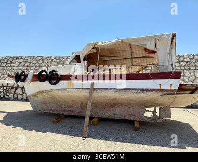 Turkiye, Antalya, molo di Finike. Una vecchia barca logora con fondo arrugginito e fangoso si appoggia sulla riva. Un ricordo delle avventure passate Foto Stock