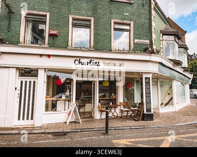 Un piccolo negozio con un cartello bianco che dice "Charities Boutique Cafe". Il negozio presenta un esterno bianco e una facciata in mattoni verdi. Kilkenny, Irlanda Foto Stock