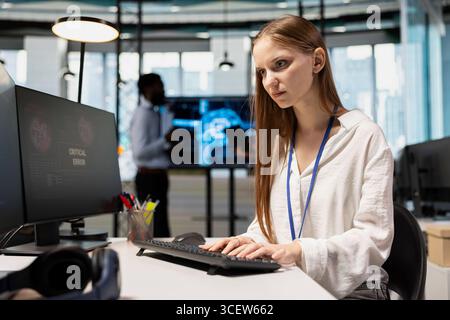 Tecnico donna che vede la finestra a comparsa di avviso di errore critico durante la regolazione dei parametri degli algoritmi di deep learning sul lavoro. Giovani lavoratori che ricevono un avviso di errore durante il lavoro con l'IA Foto Stock