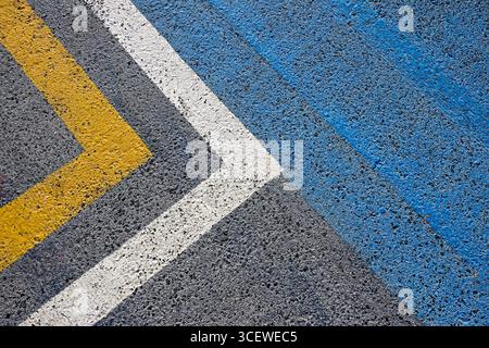 Primo piano di una strada asfaltata con linee verniciate in giallo, bianco e blu. Dettagli sull'ambiente urbano. Vista dall'alto Foto Stock