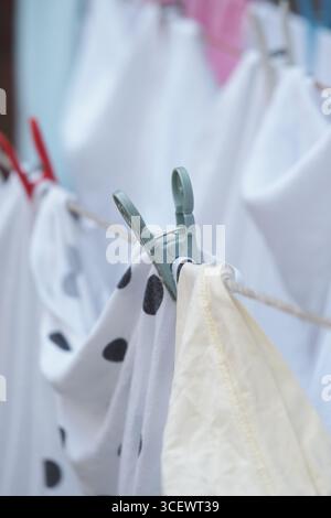 Abiti appesi a una fila in un ambiente soleggiato all'aperto Foto Stock