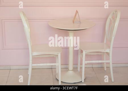 Tavolo e sedie bianchi affascinanti in un ambiente pastello Foto Stock