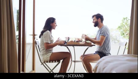 Colazione, ridere e romanticismo con una coppia sul balcone di casa insieme per un legame o la fame. Amore, mattina e sorrisi con persone felici all'aperto Foto Stock