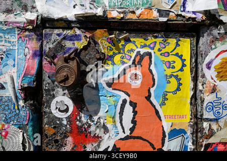 Porte coperte da poster in pasta di grano Street art, Fournier Street, Londra, Regno Unito. 12 giugno 2025 Foto Stock