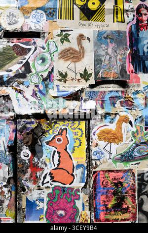 Porte coperte da poster in pasta di grano Street art, Fournier Street, Londra, Regno Unito. 12 giugno 2025 Foto Stock