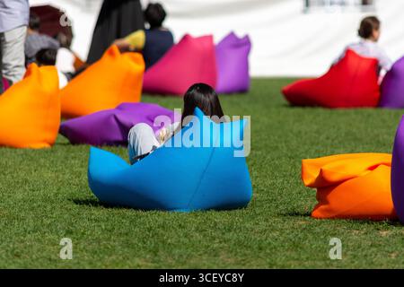 Persone che si rilassano sui sacchi di fagioli colorati in Seoul Plaza, situato di fronte al municipio di Seoul a Taepyeongno, quartiere Jung, Seoul, Corea del Sud al 1° ottobre Foto Stock