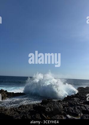 Enormi onde oceaniche si schiantano drammaticamente contro le scogliere rocciose di Devil's Tear a Nusa Penida, Bali, Indonesia, inviando potenti spruzzi in alto nel cielo. Foto Stock