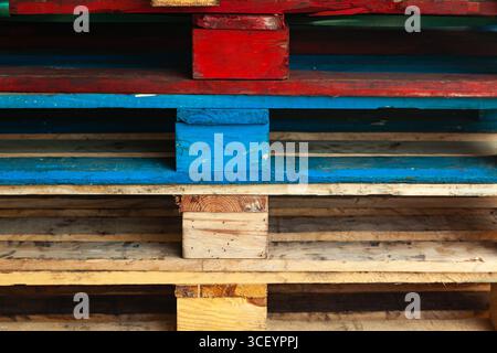 Pallet multicolore impilati uno sopra l'altro. Foto Stock