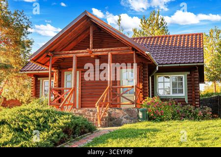Una rustica cabina in legno con tetto piastrellato e fondamenta in pietra Foto Stock