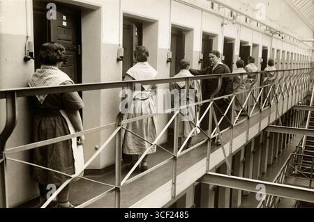 Le donne prigioniere sono all'ingresso delle loro celle in una prigione femminile a Berlino nel 1929, con una guardia femminile che dà loro istruzioni durante la loro routine quotidiana. Foto Stock