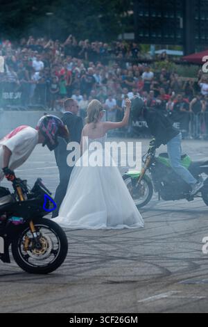 I piloti acrobatici bruciano le gomme intorno agli sposi alla festa della moto a Banja Luka, sposa e sposo in fumo Foto Stock