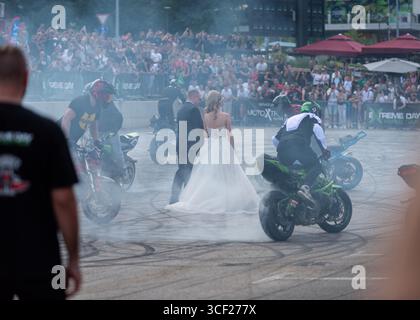I piloti acrobatici bruciano le gomme intorno agli sposi alla festa della moto a Banja Luka, sposa e sposo in fumo Foto Stock