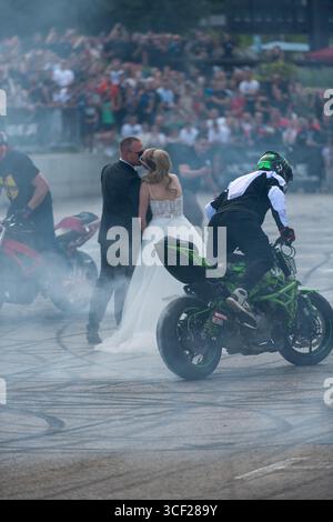 I piloti acrobatici bruciano le gomme intorno agli sposi alla festa della moto a Banja Luka, sposa e sposo in fumo Foto Stock