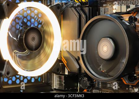La ventola di raffreddamento della CPU in primo piano funziona con la luce RGB LED mostra lo stato, all'interno del case del computer desktop e fai da te, computer ed elettronica Foto Stock