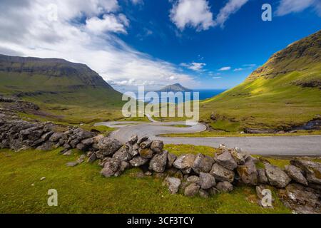Vista su una strada tortuosa che porta all'isola di Koltur sullo sfondo. Streymoy, distretto di Torshavnar, Isole Faroe, Danimarca, Scandinavia. Foto Stock