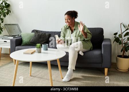 Una donna ama trascorrere il proprio tempo a casa, utilizzando il telefono mentre effettua una videochiamata Foto Stock