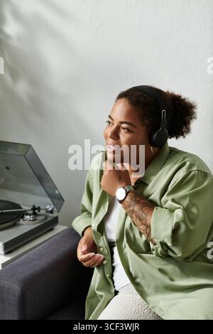 Una donna afroamericana ama trascorrere il proprio tempo a casa, ascoltando musica e sentendosi tranquilla. Foto Stock
