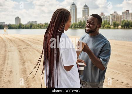 Una giovane coppia gode di un momento di gioia passeggiando lungo il fiume, abbracciando l'amore. Foto Stock