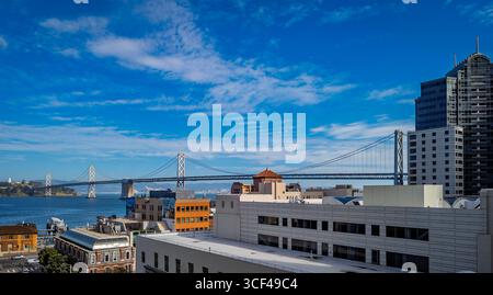 Il San Francisco Oakland Bay Bridge attraversa la baia con un paesaggio urbano e edifici in una giornata di sole limpido a San Francisco, Stati Uniti Foto Stock