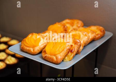 Una collezione di pasticcini danesi alle albicocche esposti su un vassoio. Questi dolci dorati e friabili sono pieni di albicocche dolci, perfetti per una deliziosa tre Foto Stock